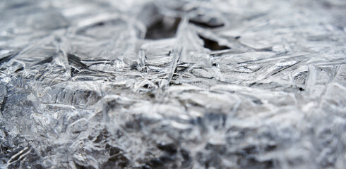 Grau-weiße Eiskristalle aus der Nähe auf einem Waldboden im Winter
