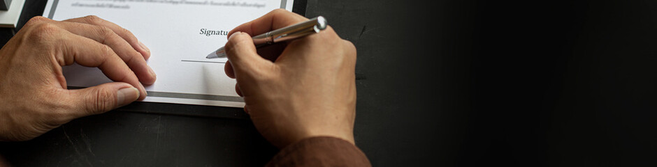 Close-up of a businessman about to sign a real estate lease document, signing an important document contract. Banner background with copy space.