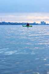 A kayaker rowing on the Danube River in a cold, cloudy winter day. Winter kayaking.