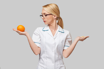 nutritionist doctor healthy lifestyle concept - holding fresh organic orange fruit and vitamin...