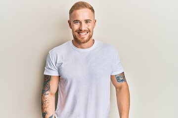 Young caucasian man wearing casual white tshirt with a happy and cool smile on face. lucky person.