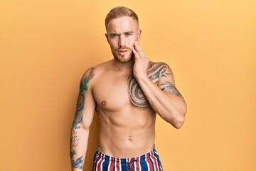 Fototapeta premium Young caucasian man wearing swimwear shirtless touching mouth with hand with painful expression because of toothache or dental illness on teeth. dentist