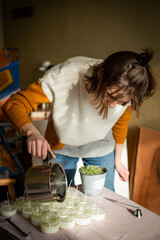 Woman pouring melted wax into amber candles container. Ecological and vegan business. Soya wax candle accessories. Handmade with love. Remote work, online shop, workplace