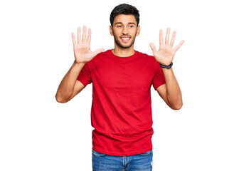 Fototapeta premium Young handsome man wearing casual red tshirt showing and pointing up with fingers number ten while smiling confident and happy.