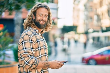 Young caucasian man smiling happy using smartphone at the city.