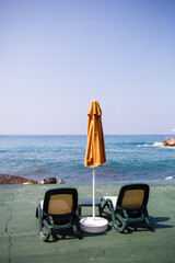 Beautiful sun loungers and beach umbrellas at the marina by the sea for relaxation