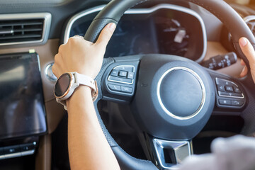 woman driver driving a car on the road, hand controlling steering wheel in electric modern...
