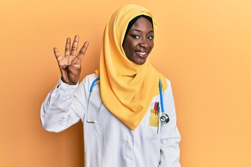 Beautiful african young woman wearing doctor uniform and hijab showing and pointing up with fingers...