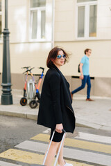 Beautiful woman in black dress on a background of an urban landscape with a suitcase