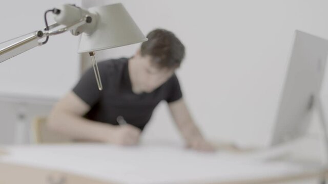 Young male person at desk drawing.