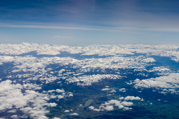 Aerial view of  Alps and Pyrenees mountains and scattered clouds from the aircraft plane window