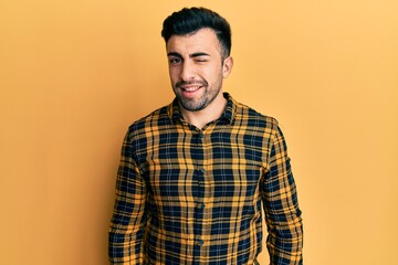 Young hispanic man wearing casual clothes winking looking at the camera with sexy expression, cheerful and happy face.