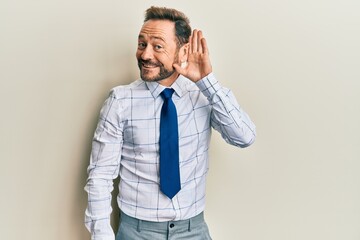 Middle age businessman wearing business shirt and tie smiling with hand over ear listening and...