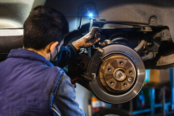 Mechanic repairing brakes on the car. Mask. Selective focus disc brake on car. Vehicle repair concept.