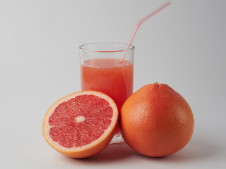 Fresh grapefruits and a glass of grapefruit juice on a white wooden background with a copy space. Close-up.