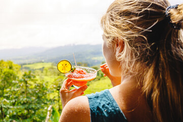 Blonde woman sipping a cocktail in front of the forest