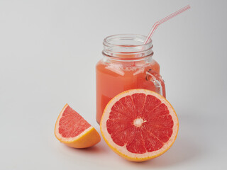 Fresh grapefruits and a glass of grapefruit juice on a white wooden background with a copy space. Close-up.