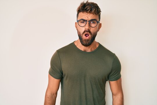 Young hispanic man wearing casual clothes and glasses scared and amazed with open mouth for surprise, disbelief face