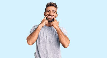 Young hispanic man wearing casual clothes smiling with open mouth, fingers pointing and forcing...