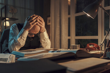 Exhausted professor sitting at desk and studying