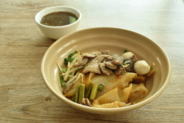 dry large rice noodles topping slice braised and fermenting with meatball dressing black sweet soy sauce on bowl eat couple brown herb soup