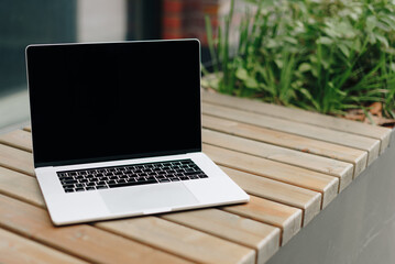 Laptop on a wooden bench outdoors