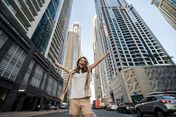 Young woman standing in awe underneath skyscrapers and office buildings in an urban metropolis. Low angle view.