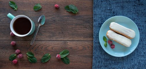 
Dessert ingredients. Food background. Mint leaves, fresh raspberries, a cup of tea, eclairs on a plate.