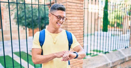 Young hispanic student smiling happy pointing with finger to the watch at street of city