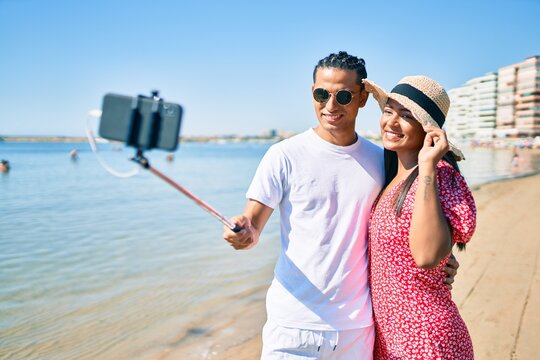 Young latin couple smiling happy making selfie by the smartphone at the beach.