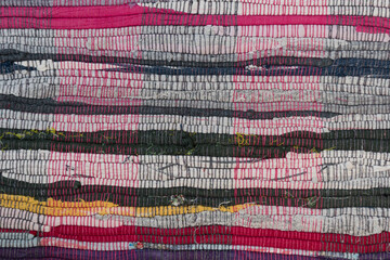 A rug made of multicolored strips of fabric. Handwork. Close-up, background and texture