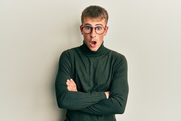 Fototapeta premium Young caucasian man wearing glasses with arms crossed gesture afraid and shocked with surprise and amazed expression, fear and excited face.