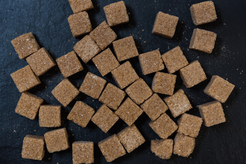 Cane sugar cubes, top view. Black background. Brown sugar texture