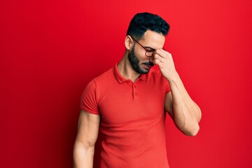 Young hispanic man wearing casual clothes and glasses tired rubbing nose and eyes feeling fatigue and headache. stress and frustration concept.