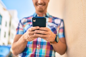 Young caucasian man smiling happy using smartphone at the city.