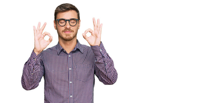 Handsome caucasian man wearing casual clothes and glasses relax and smiling with eyes closed doing meditation gesture with fingers. yoga concept.