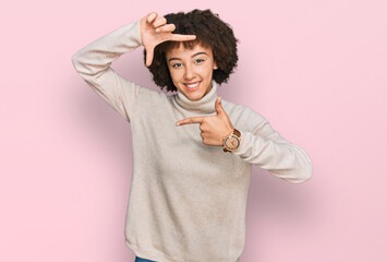 Young hispanic girl wearing wool winter sweater smiling making frame with hands and fingers with happy face. creativity and photography concept.
