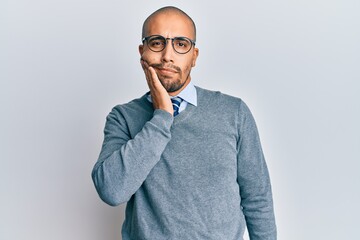 Hispanic adult man wearing glasses and business style touching mouth with hand with painful expression because of toothache or dental illness on teeth. dentist