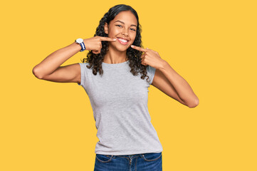 Young african american girl wearing casual clothes smiling cheerful showing and pointing with fingers teeth and mouth. dental health concept.