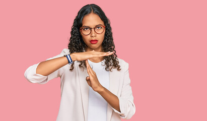 Young african american girl wearing business clothes doing time out gesture with hands, frustrated...