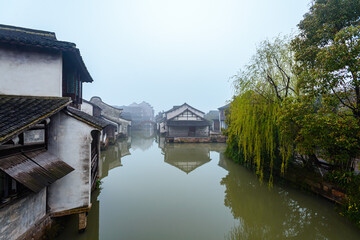 Fototapeta na wymiar WUZHEN,CHINA-MARCH 6,2012: Ancient buildings along the canal. Morning fog over the city.