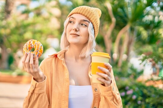 Young blonde girl smiling happy having breakfast at the park.