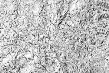 Texture of crumpled aluminum kitchen foil. Top view closeup.