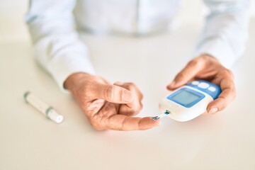 Close up of man with diabetes using insuline glucometer with blood from the finger
