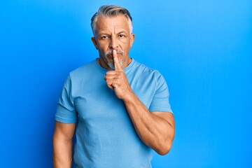 Middle age grey-haired man wearing casual clothes asking to be quiet with finger on lips. silence and secret concept.