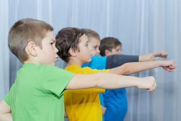Boys in multicolored t-shirts practice punching on a light background
