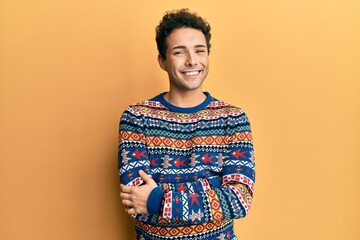 Young handsome man wearing casual winter sweater happy face smiling with crossed arms looking at...