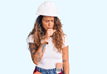 Young hispanic woman with tattoo wearing hardhat and builder clothes feeling unwell and coughing as symptom for cold or bronchitis. health care concept.