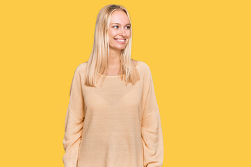 Obraz premium Young blonde girl wearing casual clothes looking away to side with smile on face, natural expression. laughing confident.