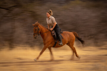 Slow pan of blonde riding by woods
